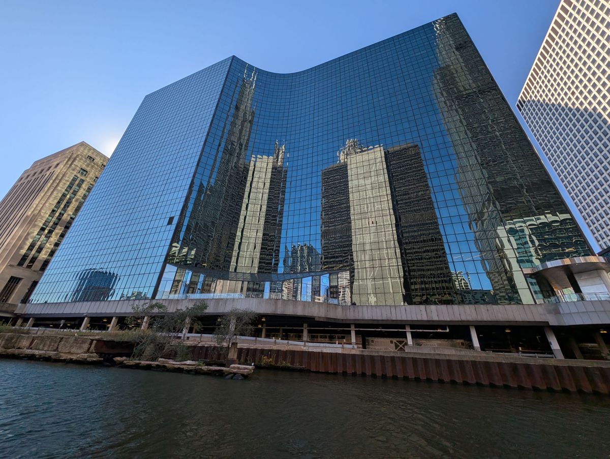 A mirrored tower reflecting its neighbors, with Amtrak trains running underneath