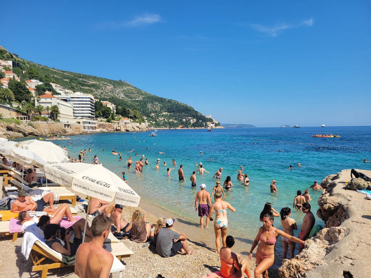 A crowded beach below the walls