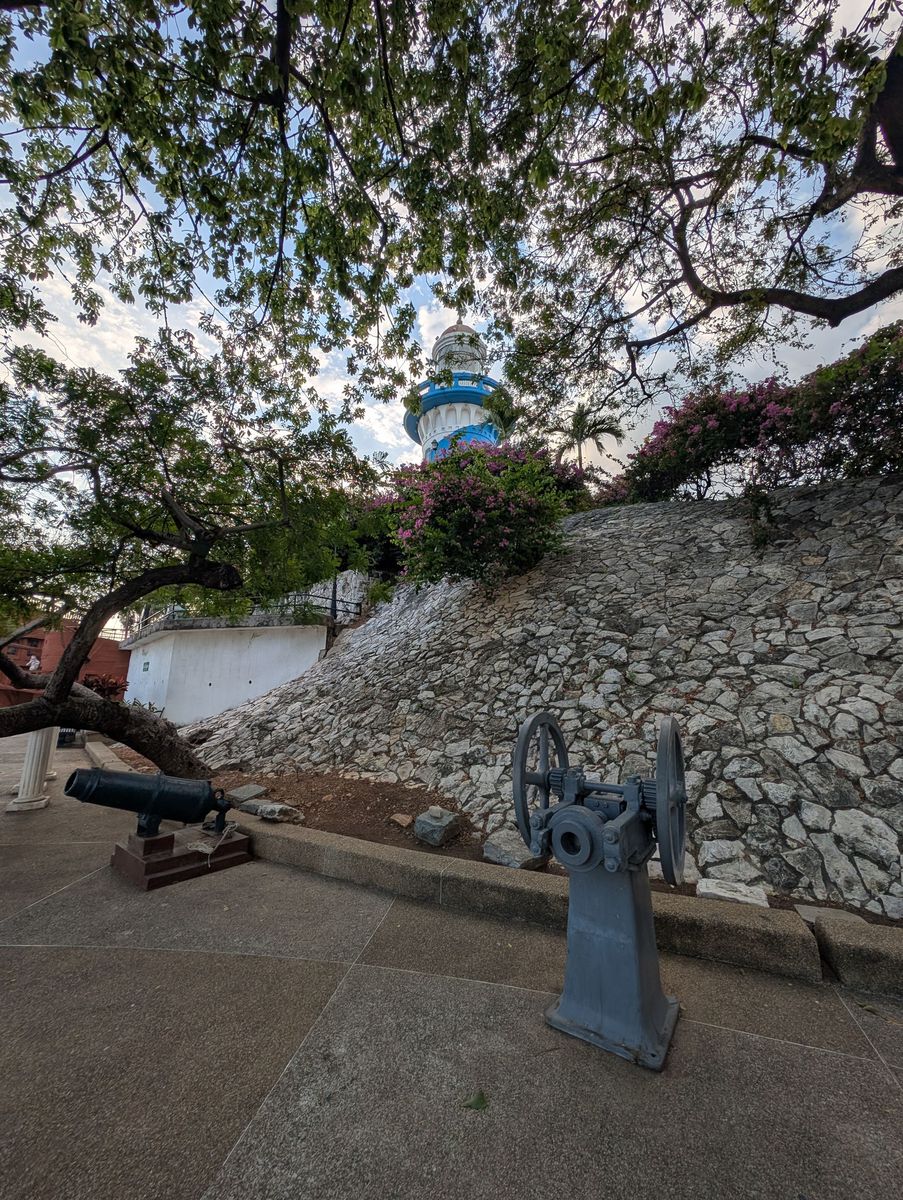 The lighthouse above a stone slope and bougainvillea