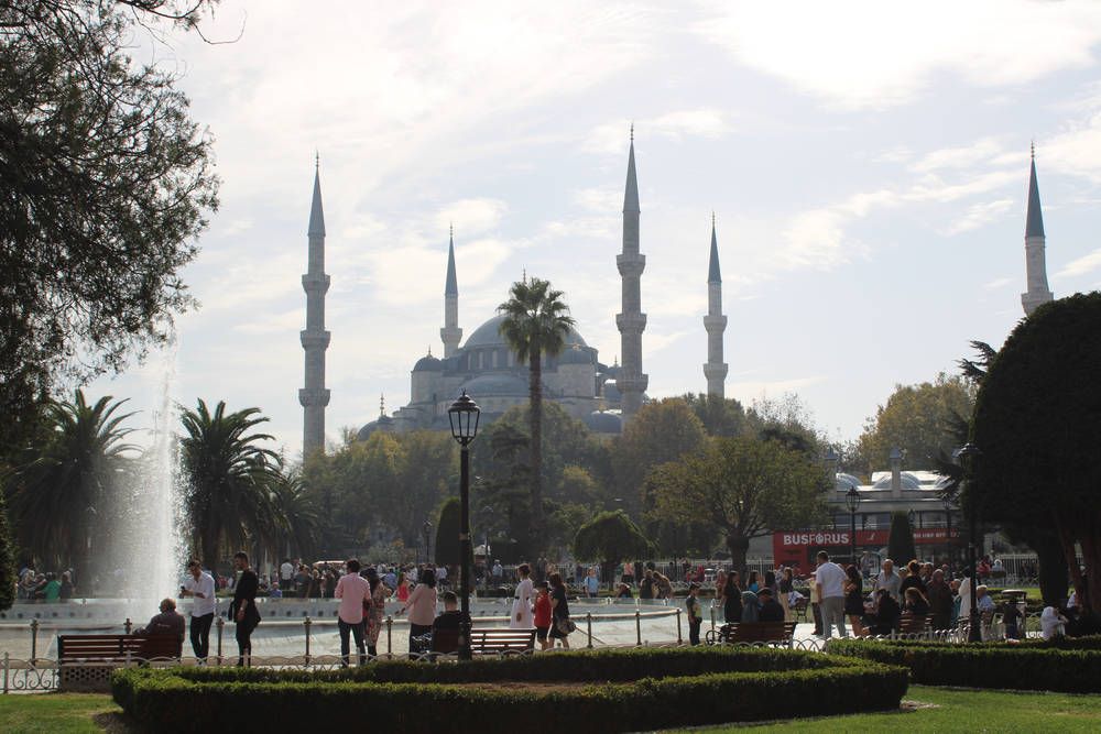 A mosque with six minarets beyond a fountain
