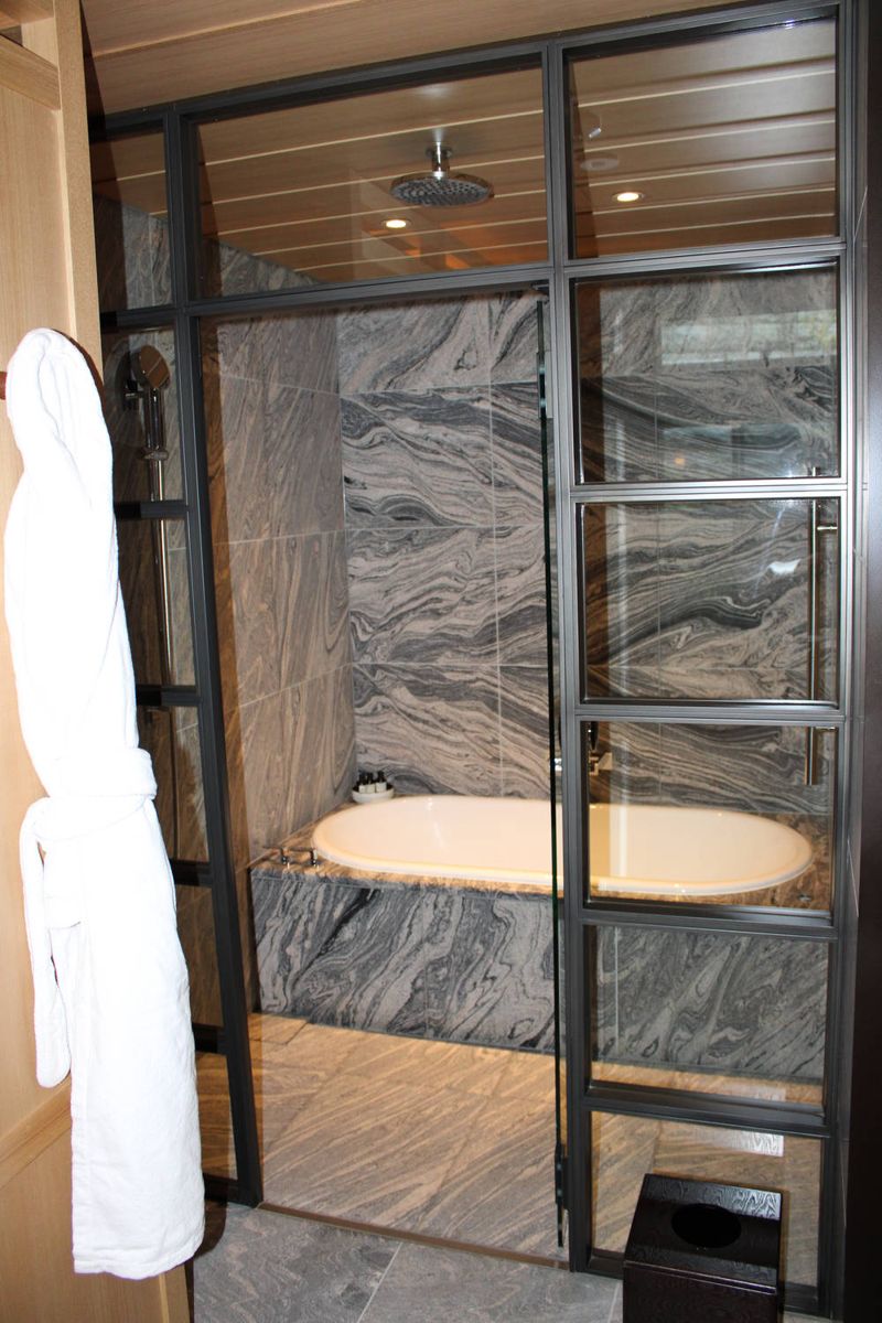 The bath behind glass, a robe hanging by the door