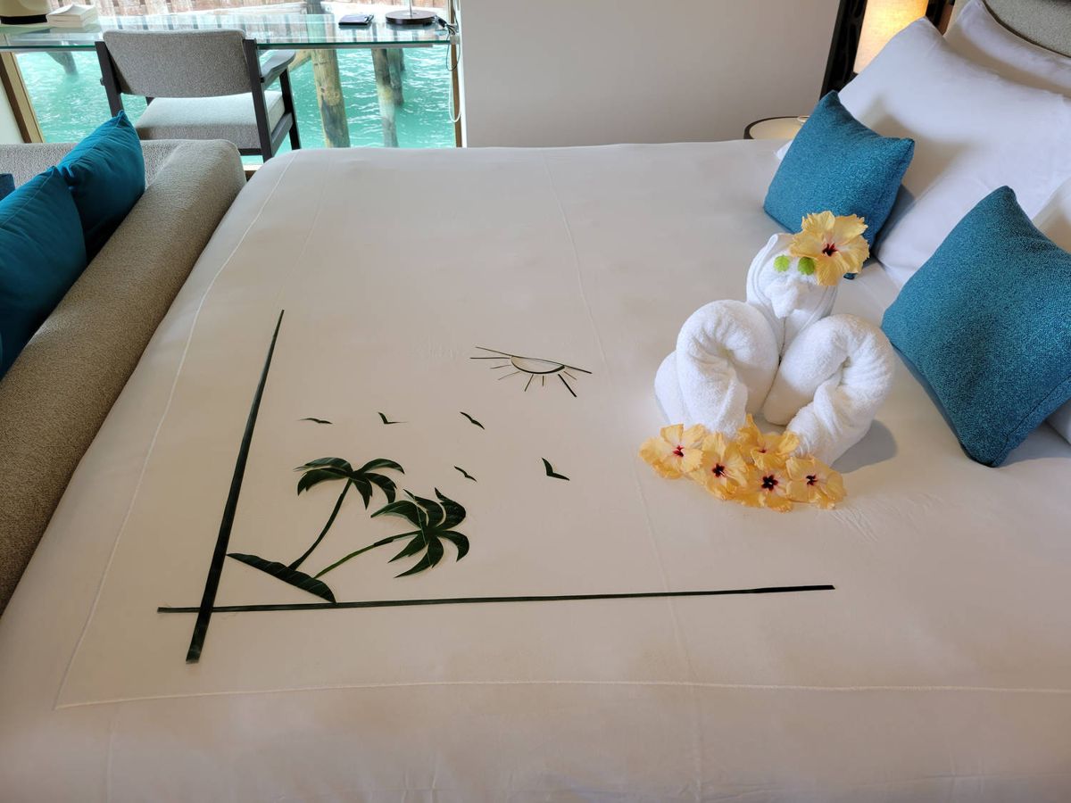 A towel animal and flowers on the bed