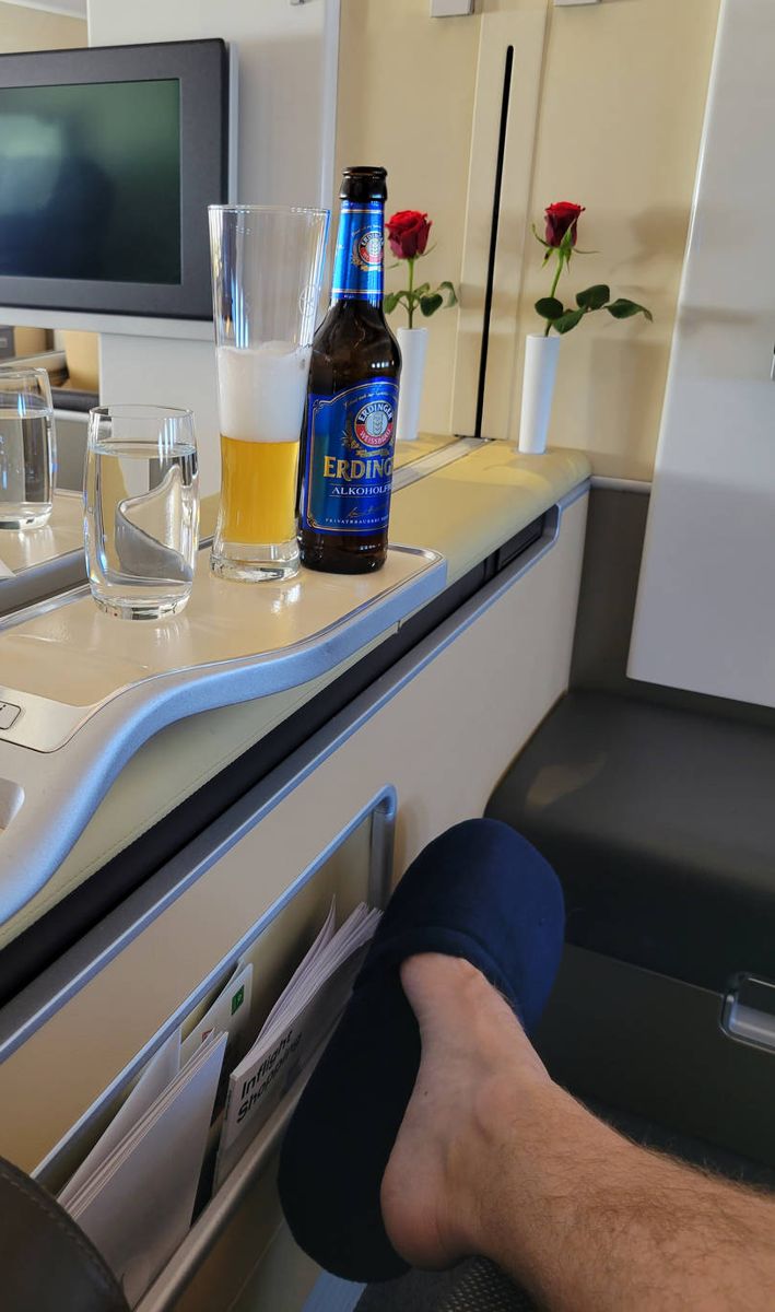 A water glass and an Erdinger Alkoholfrei by the seat, feet up