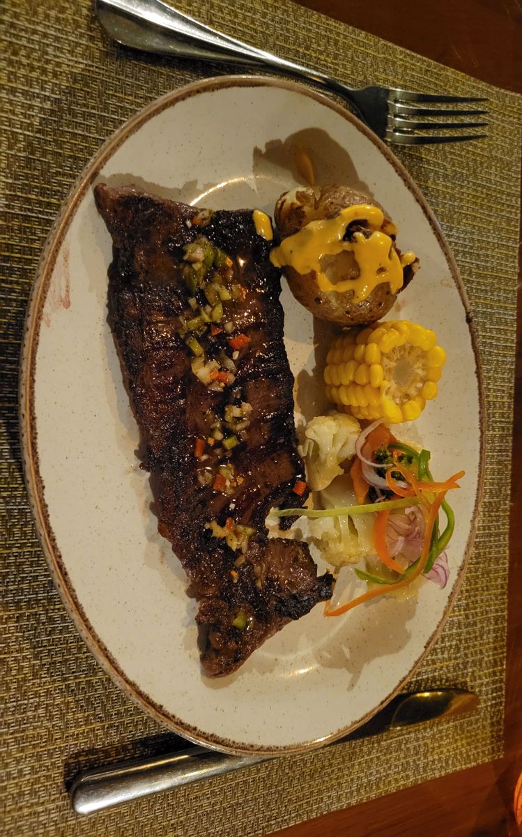 Steak with a baked potato and corn