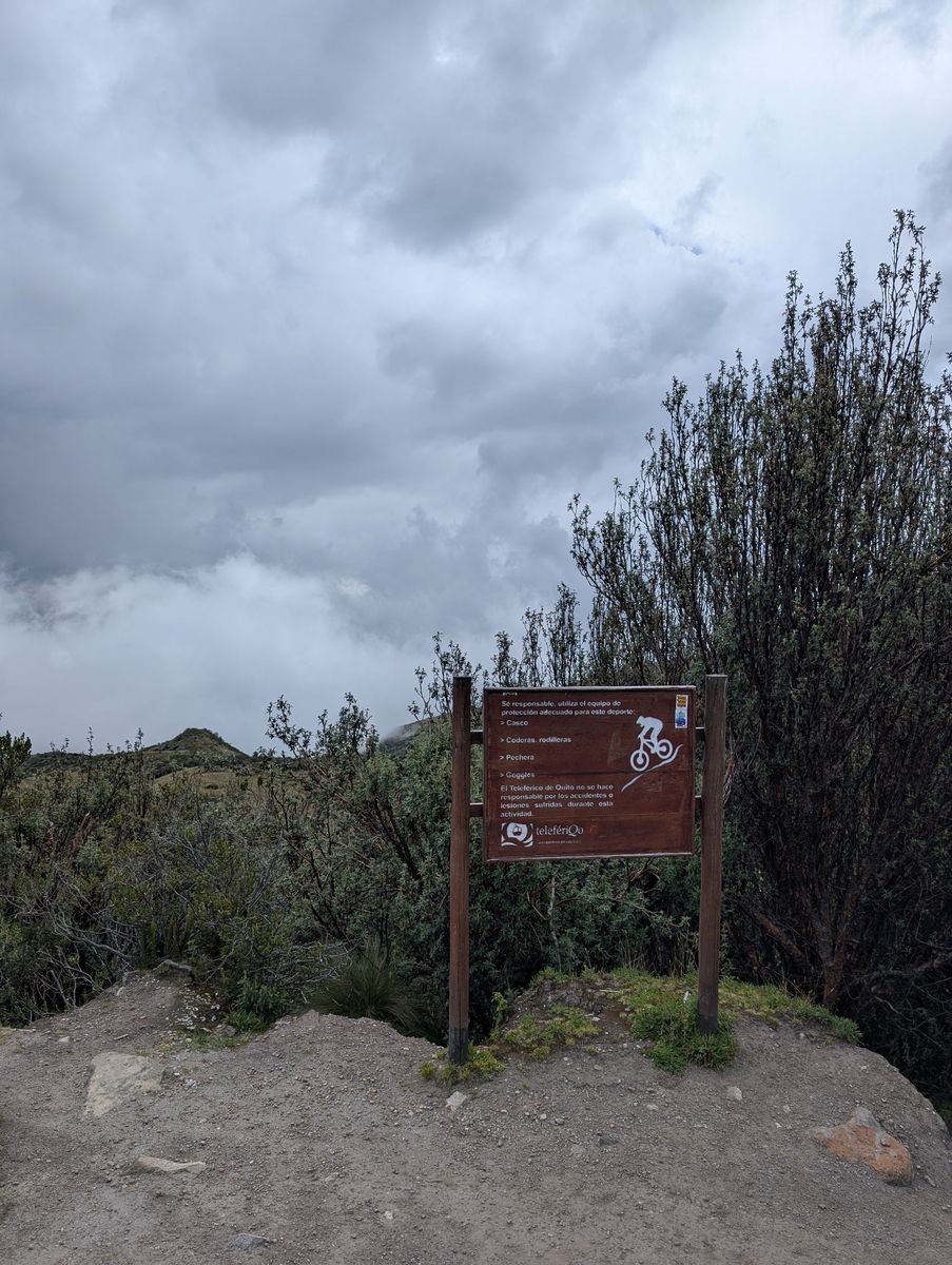 A TelefériQo sign for the downhill bike trail: helmet, pads, chest protector, goggles