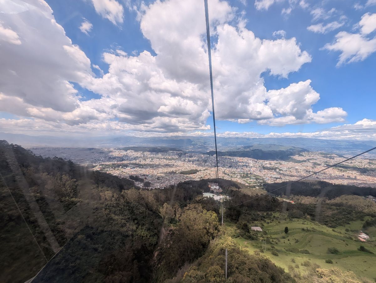 The cable climbing over the forest, with Quito below