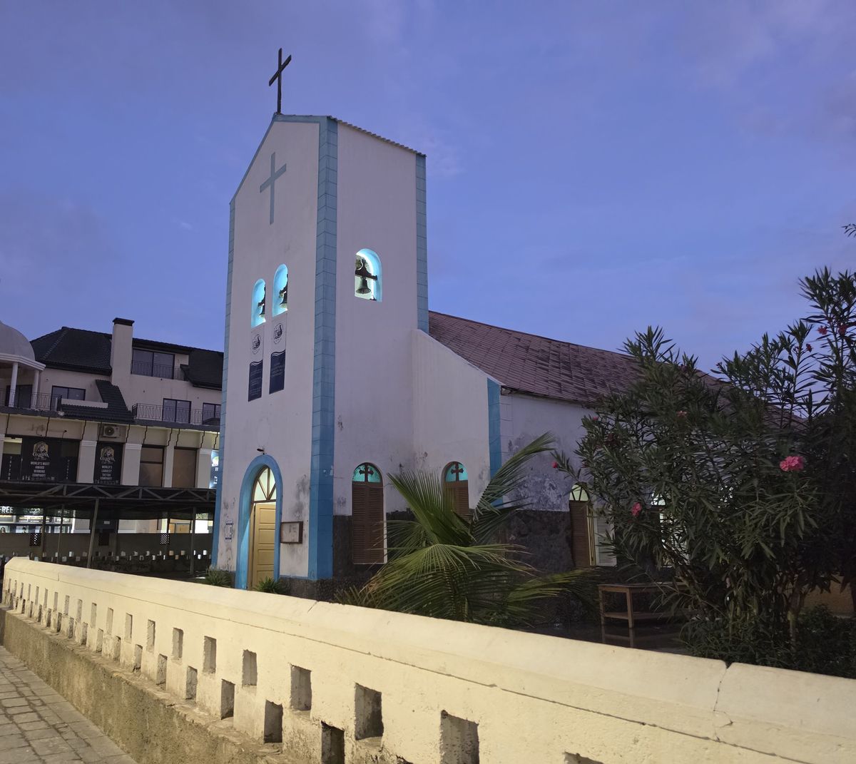 A small white church in town at dusk
