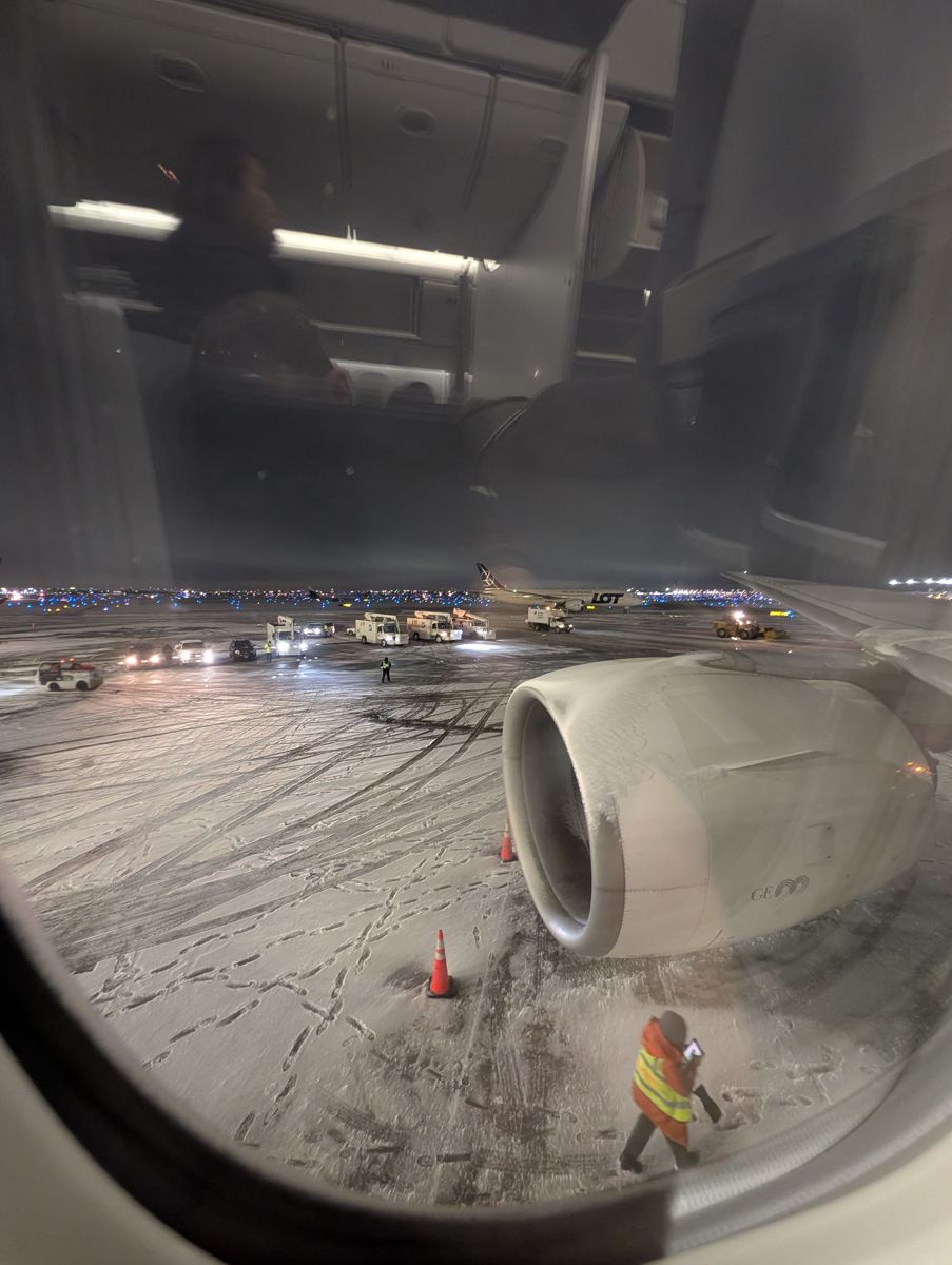 A snowy ramp at O'Hare, with a LOT Dreamliner taxiing past