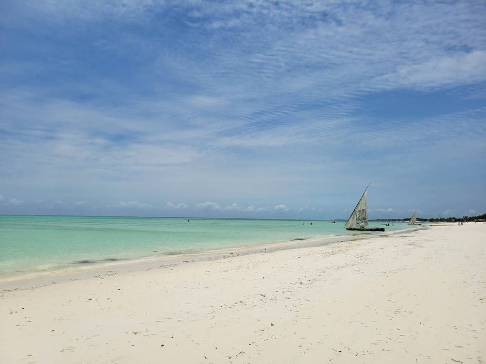 A sailboat off the beach at high tide
